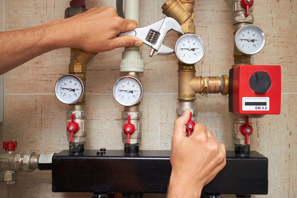 Person Using A Wrench On Pipes With Pressure Gauges And Valves
