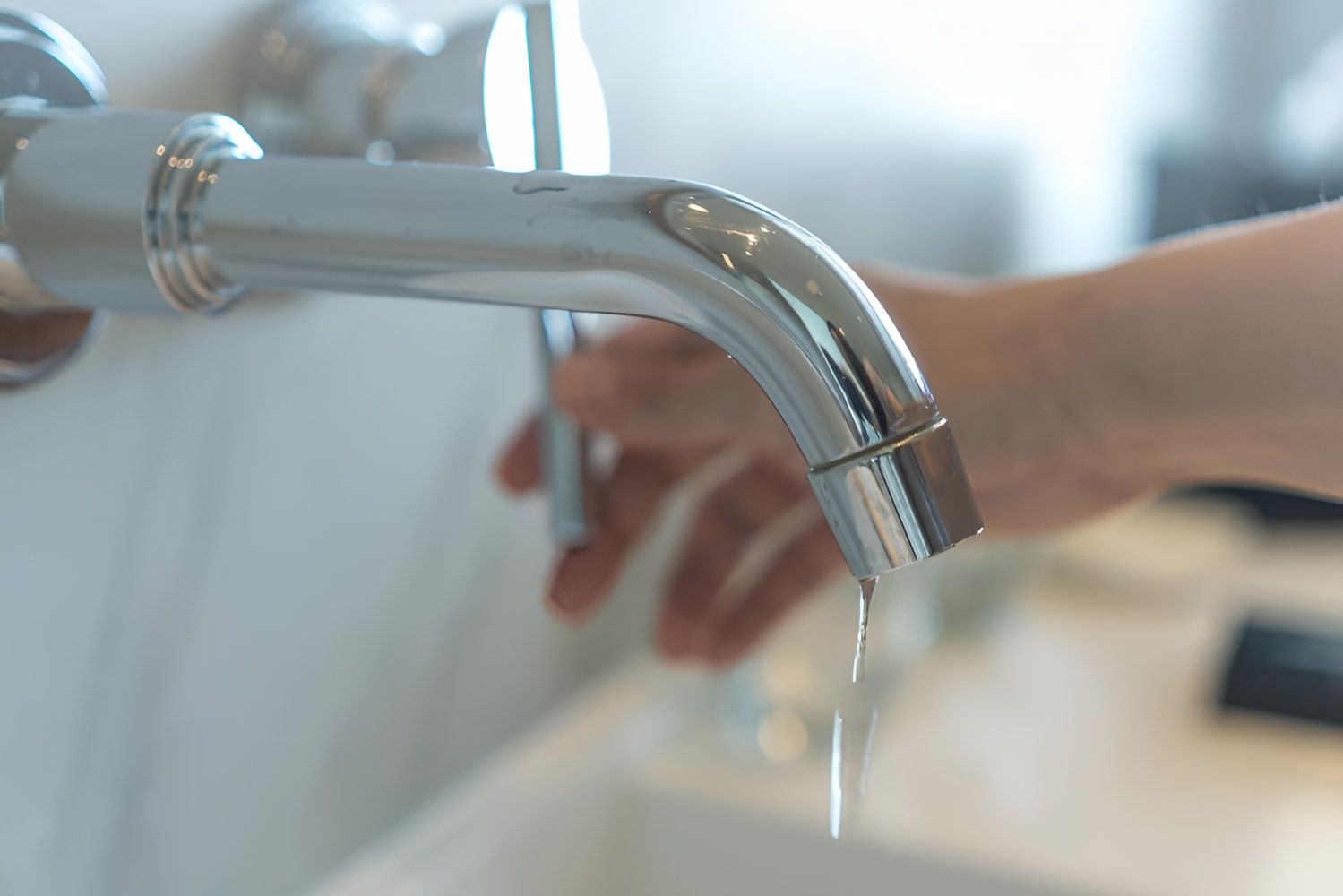 A Person Is Holding A Faucet With Water Dripping From It — GPS Plumbing, Drainage & Gasfitting In Dubbo, NSW