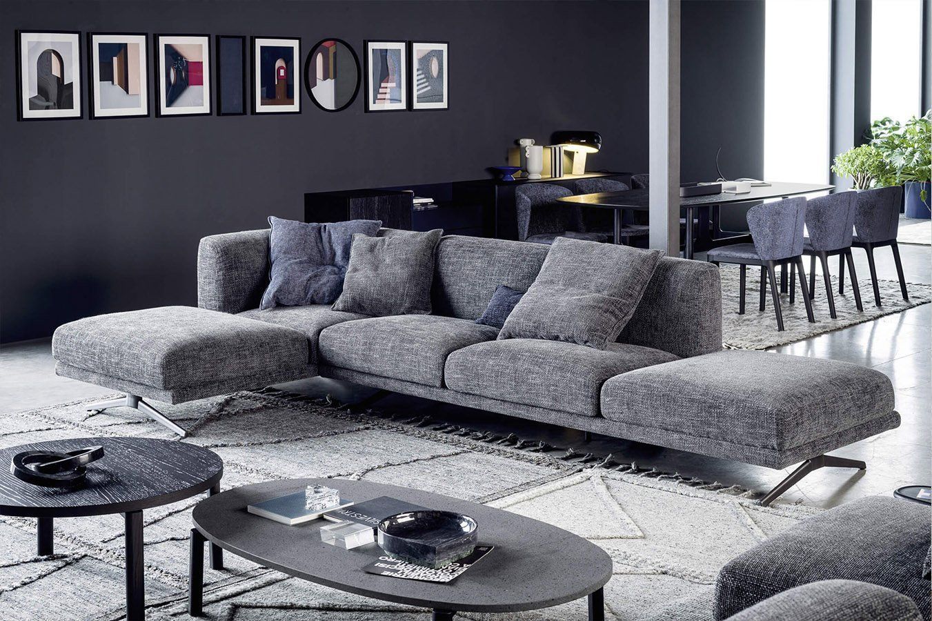 Divano componibile grigio in un soggiorno moderno con tappeto e opere d'arte.