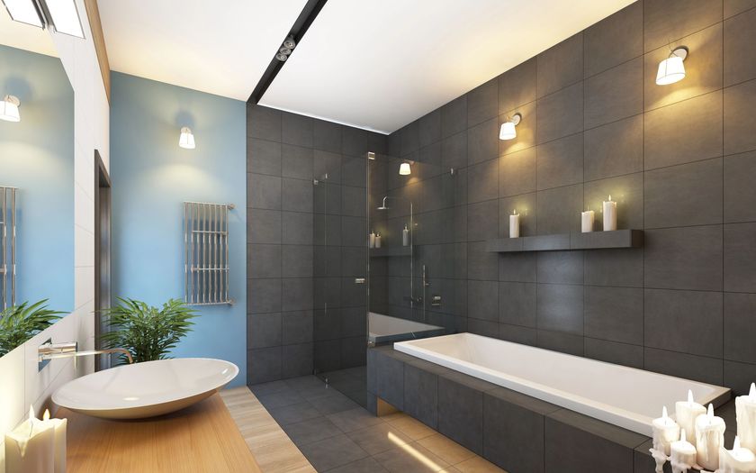 Bagno moderno con pareti piastrellate grigie, vasca bianca e parete con dettagli blu.