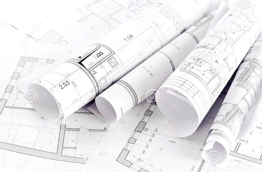 Progetti architettonici arrotolati sopra progetti aperti.