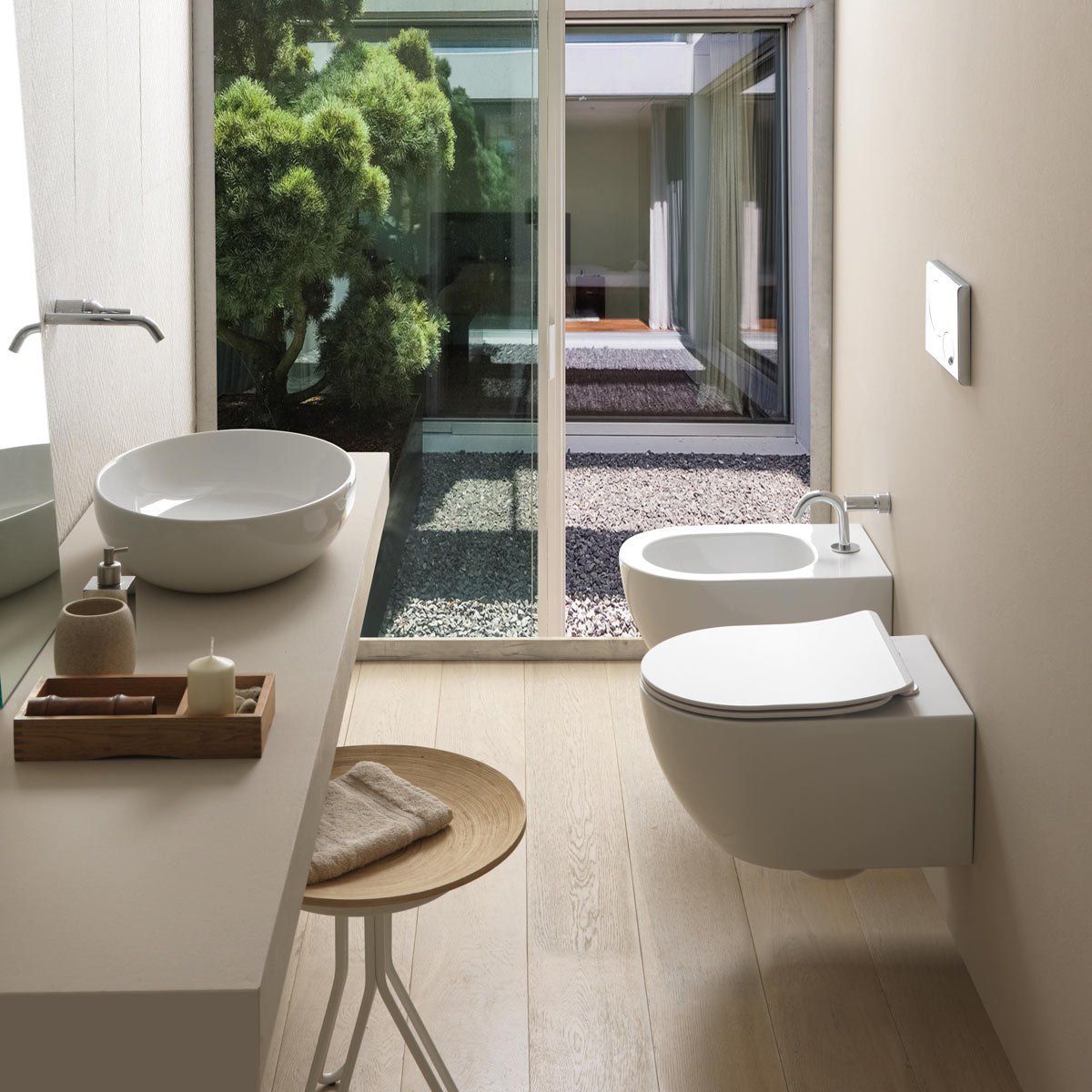 Bagno moderno con lavandino, WC e bidet. Un'ampia finestra si affaccia su un piccolo cortile esterno.