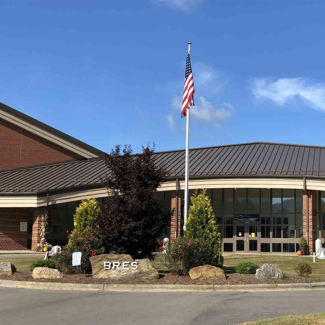 A large brick building with an american flag flying in front of it.