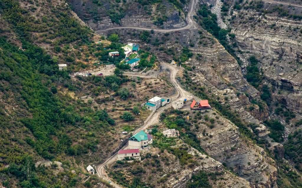Pueblo de montaña con casas de colores situadas en una empinada ladera junto a un barranco rocoso