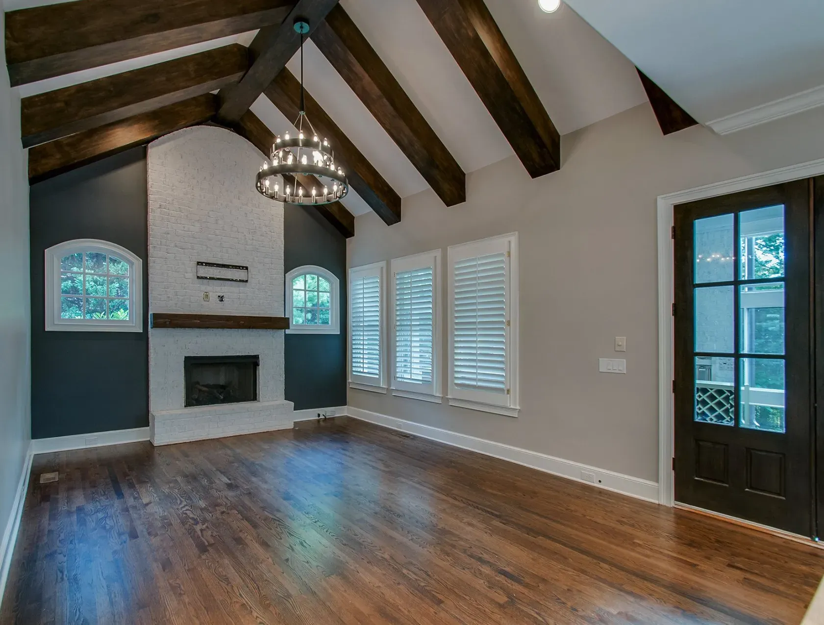 Spacious living room with vaulted wood-beam ceiling, fireplace, chandelier, and hardwood floors