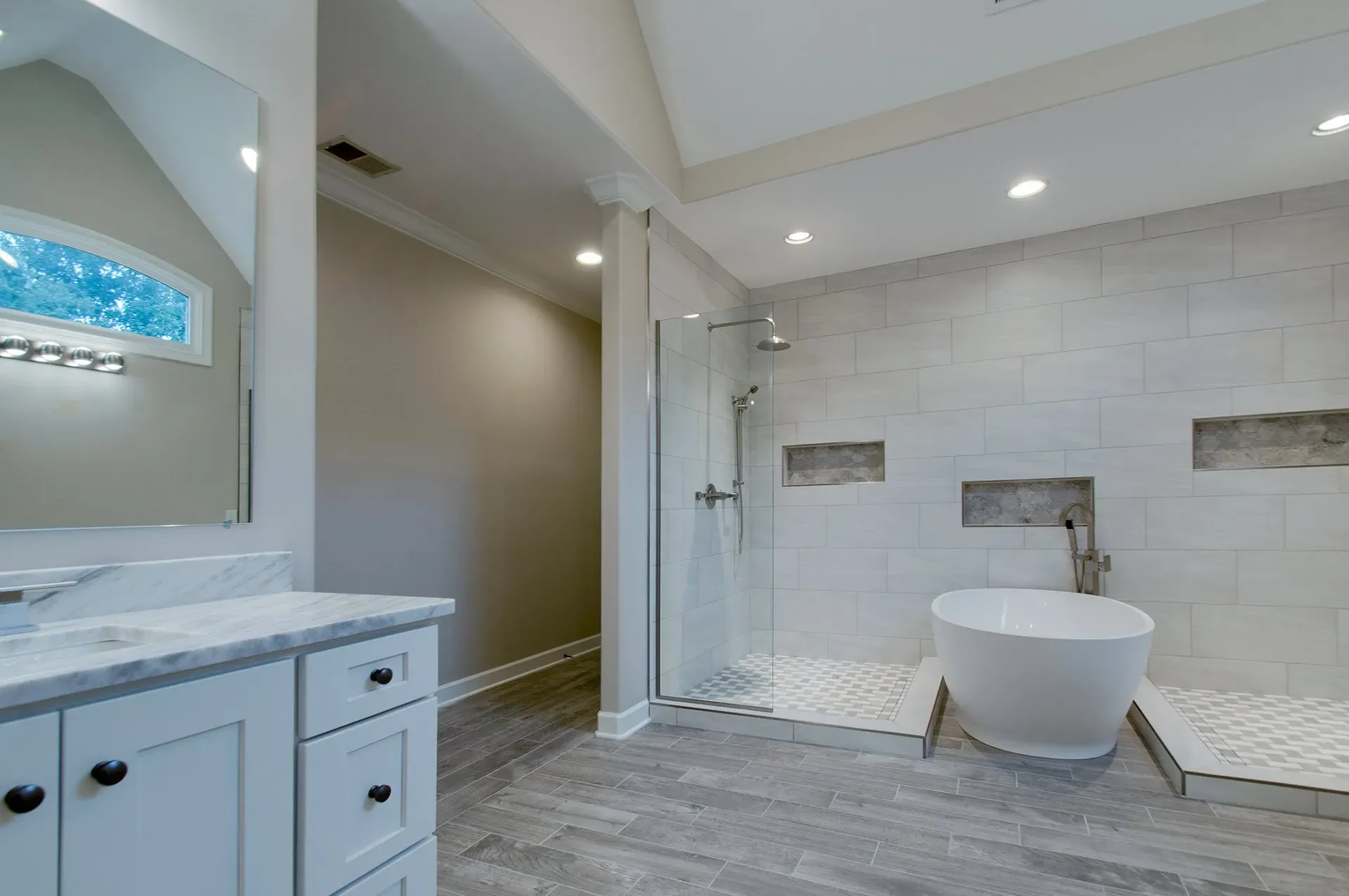 Modern bathroom with freestanding tub, walk-in shower, white vanity, and gray tile flooring