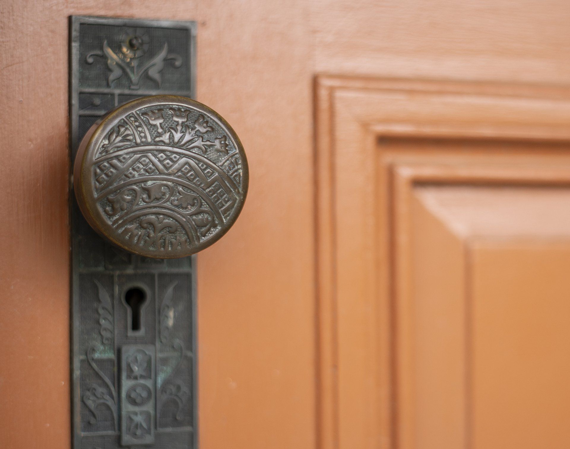 Close-up of an ornate antique doorknob and keyhole on a wooden door