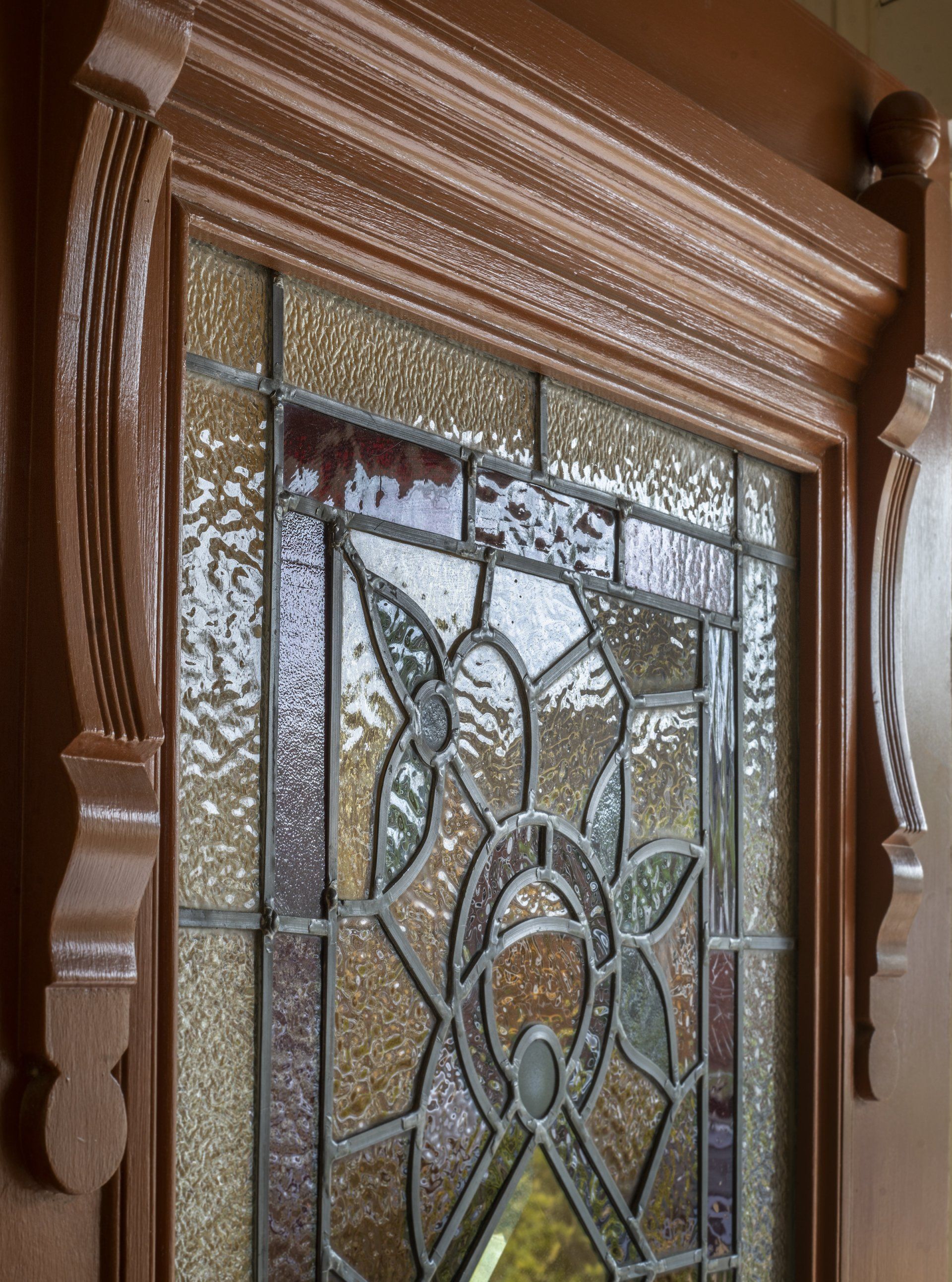 Decorative stained-glass front door with frosted panels and a carved wooden frame