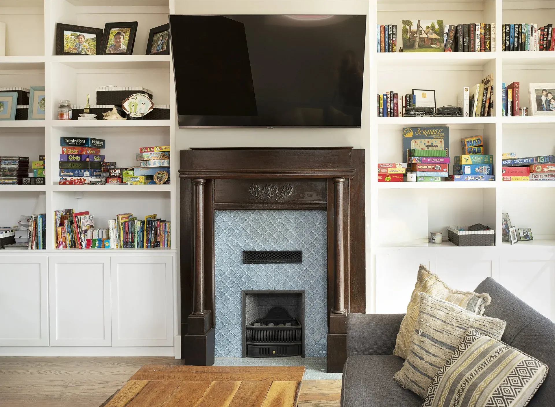 Living room with built-in bookshelves, a wall-mounted TV, and a dark fireplace mantel