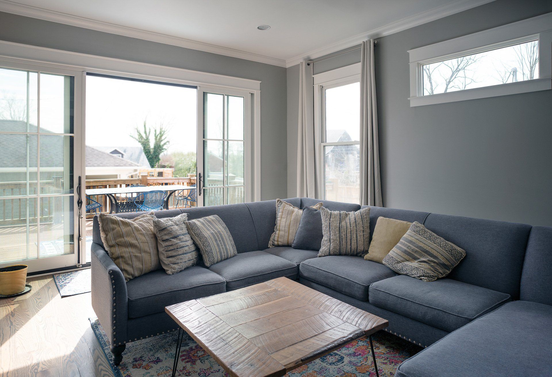 Bright living room with a gray sectional sofa, coffee table, and large sliding glass doors.