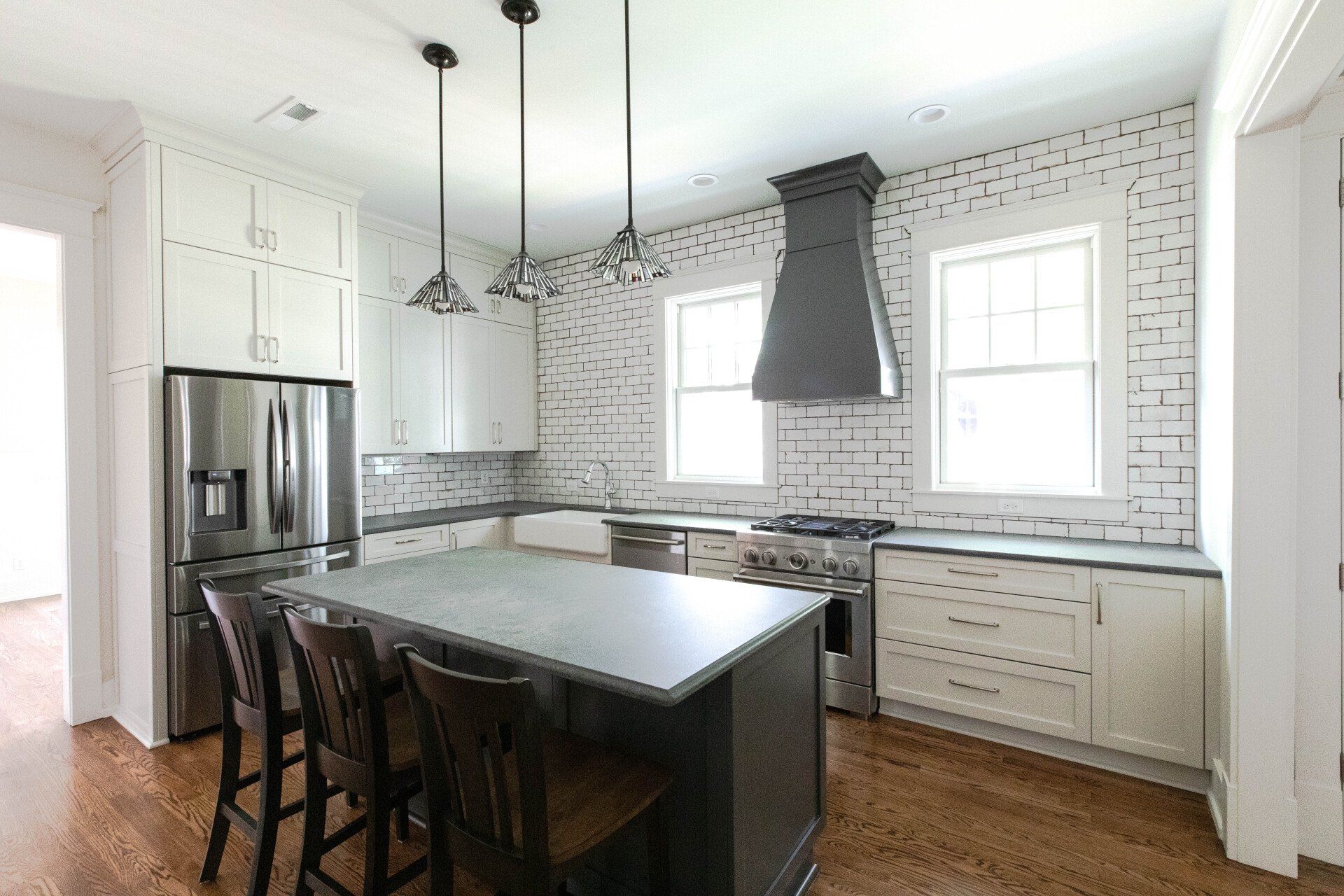 Modern kitchen with stainless steel fridge, black island, white cabinets, and patterned tile backsplash