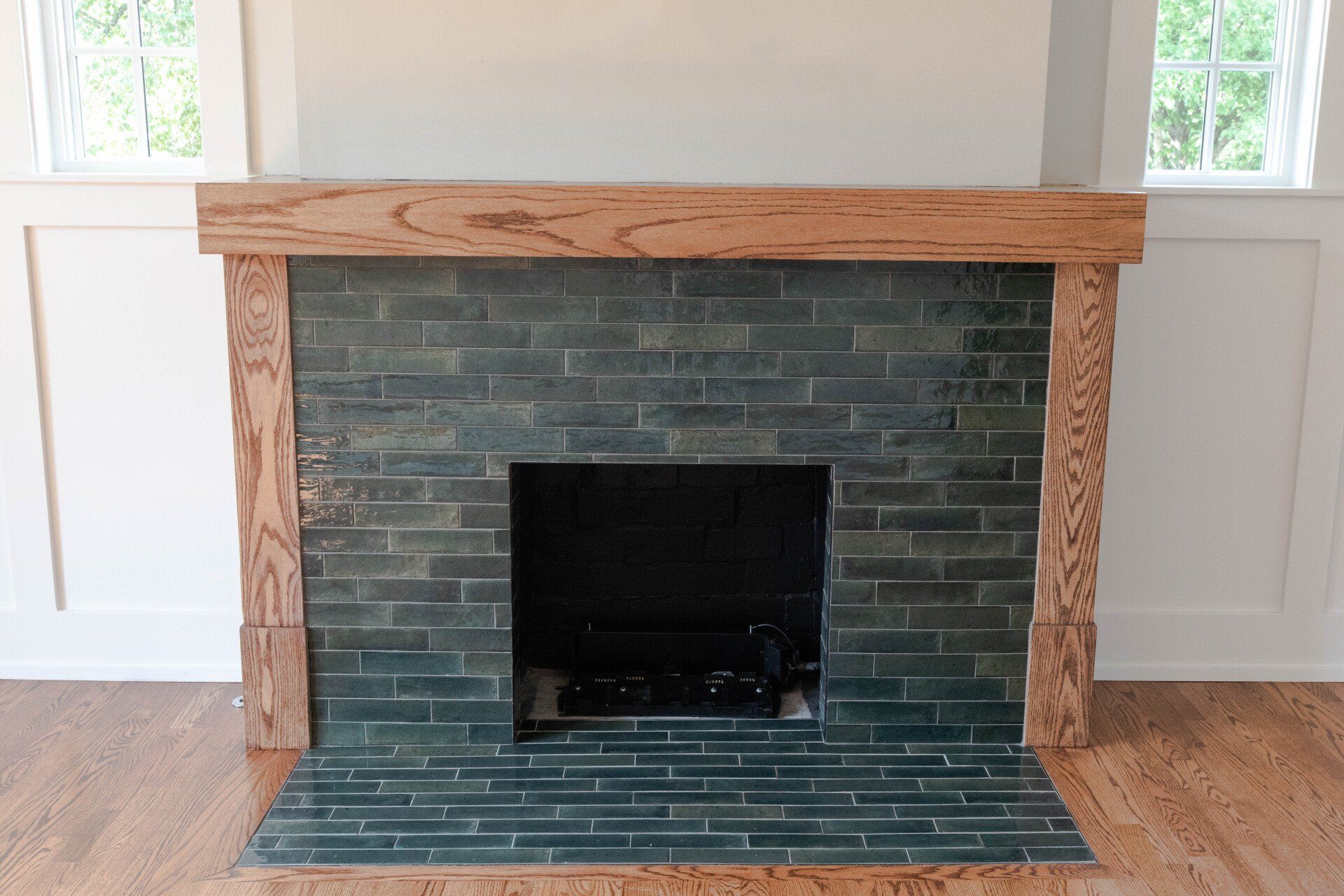 Stone fireplace with dark tile surround and wooden mantel in a bright room