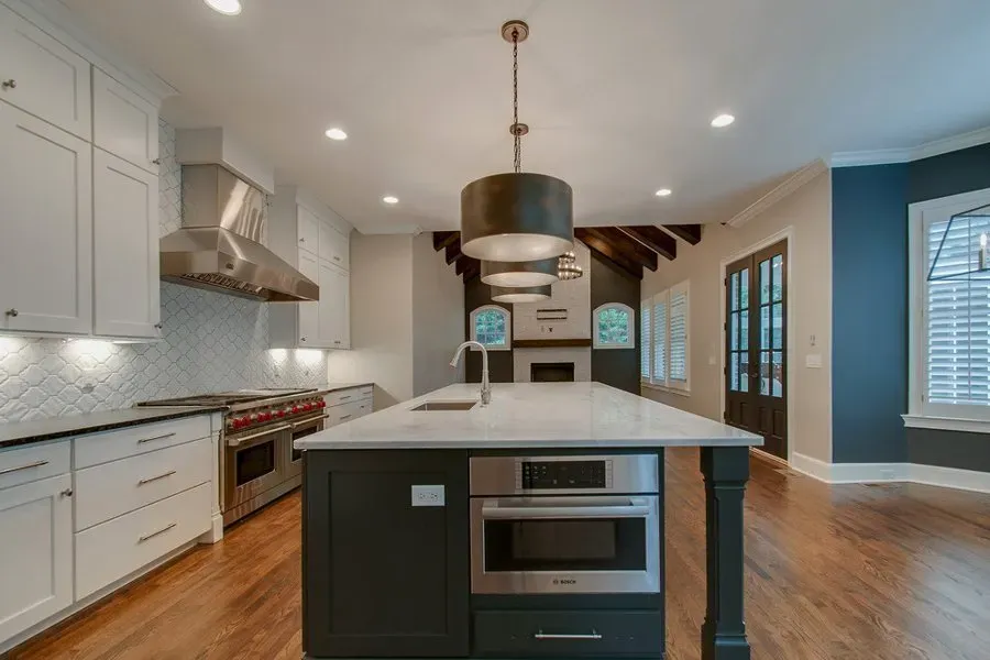 Modern kitchen with white cabinets, large island, stainless steel appliances, and hardwood floors