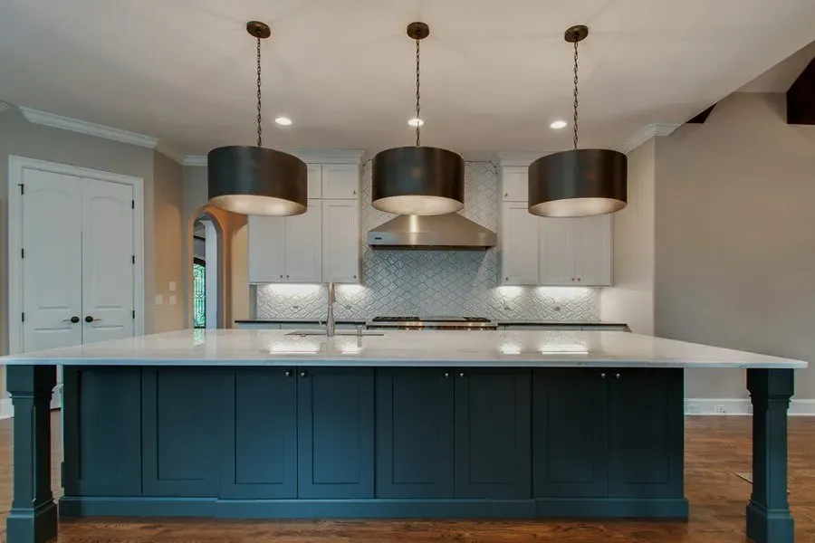 Modern kitchen with teal island, white countertops, and three pendant lights