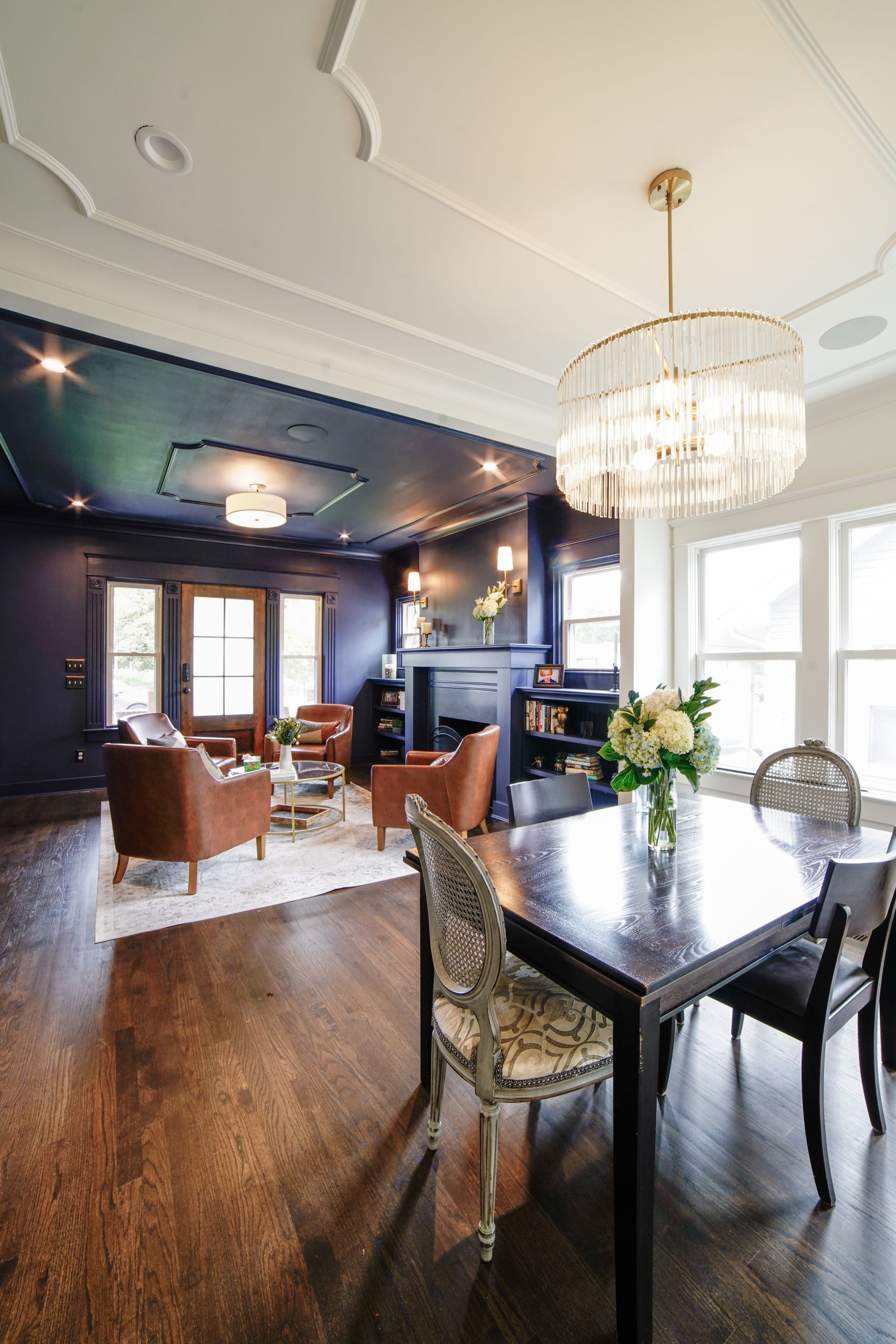 Elegant dining room with chandelier, dark walls, hardwood floors, and upholstered chairs in a spacious home interior