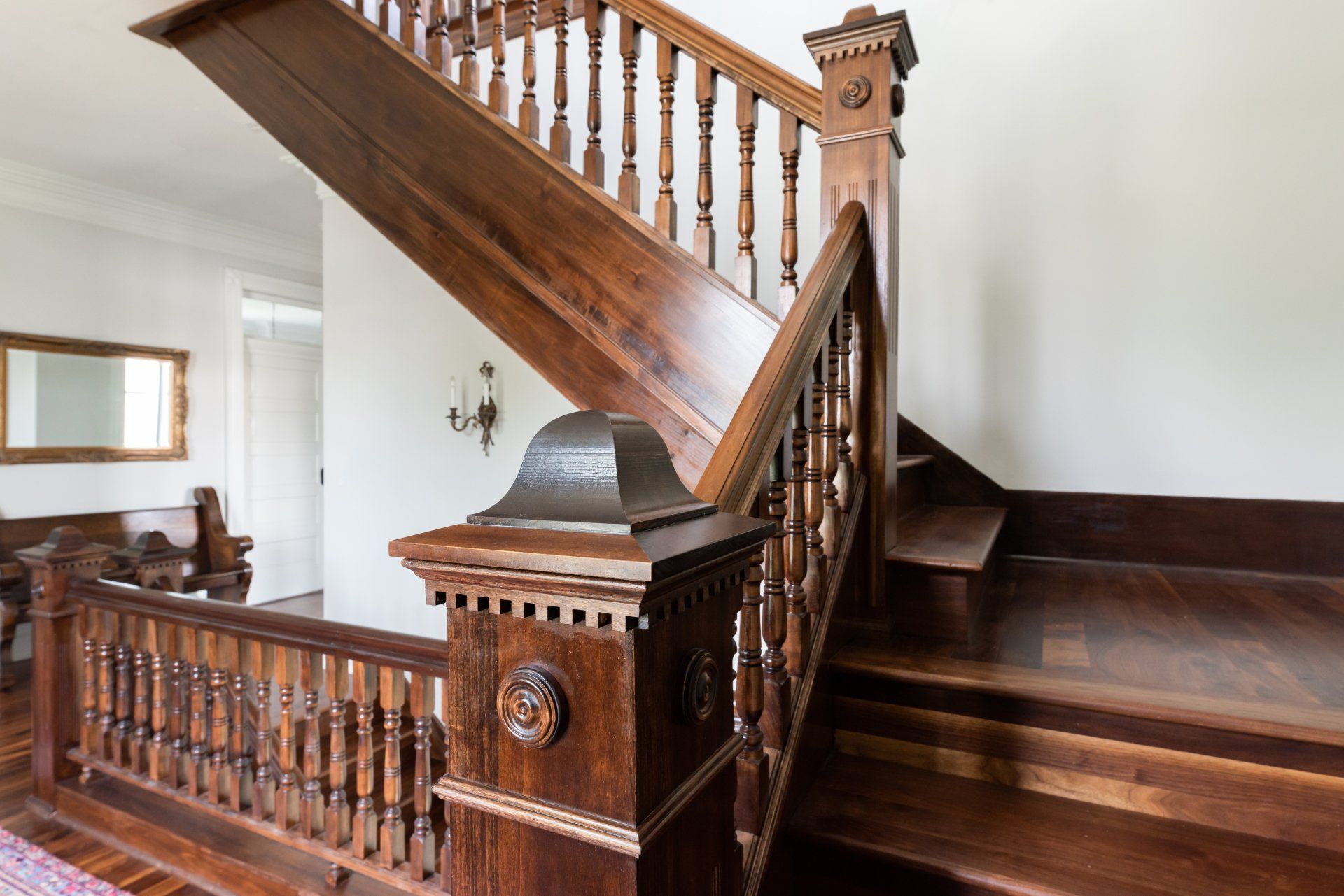Wooden staircase with carved banister and dark polished steps in a bright interior hall