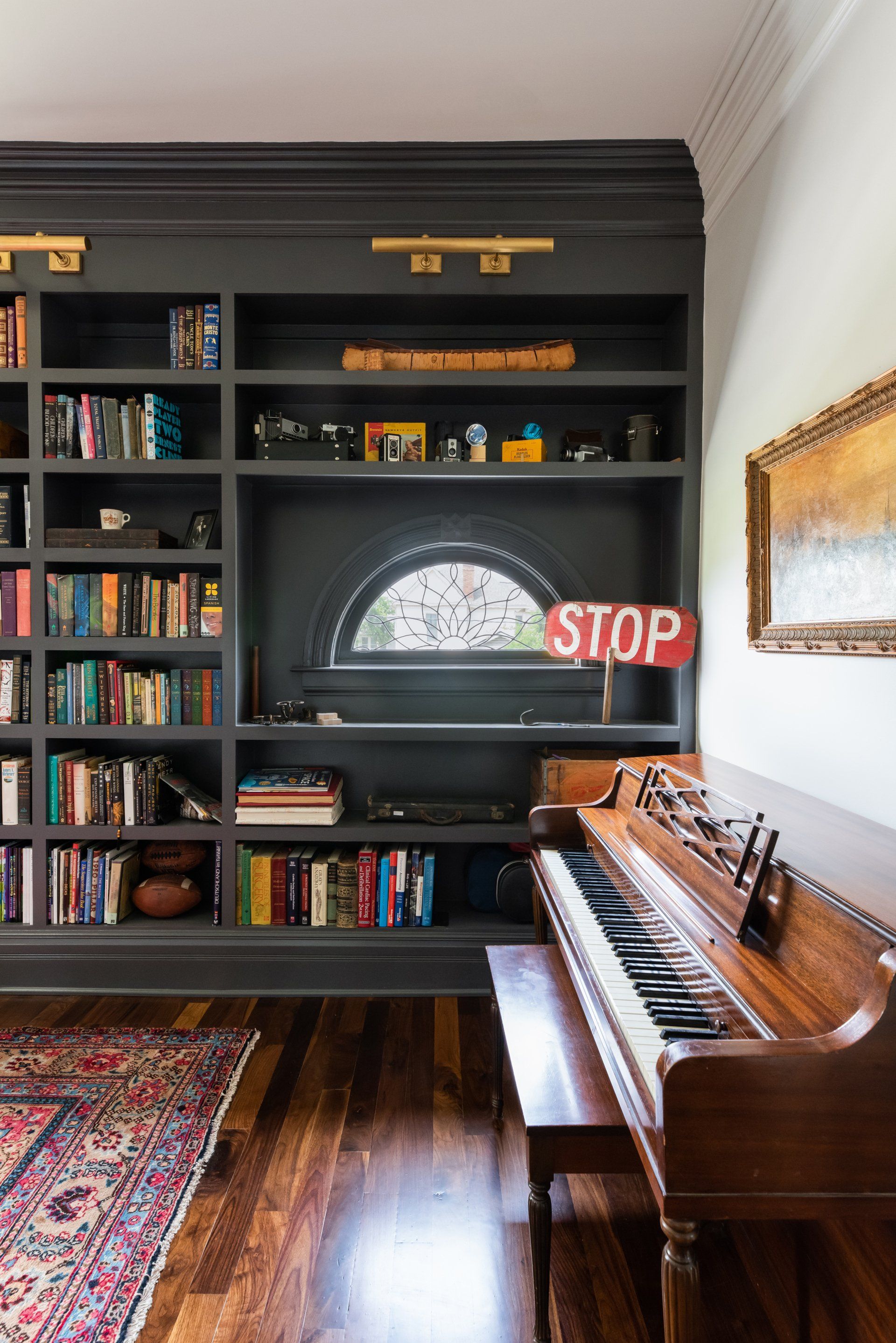 Built-in bookshelves and piano in a cozy room with a window sign reading “STOP”