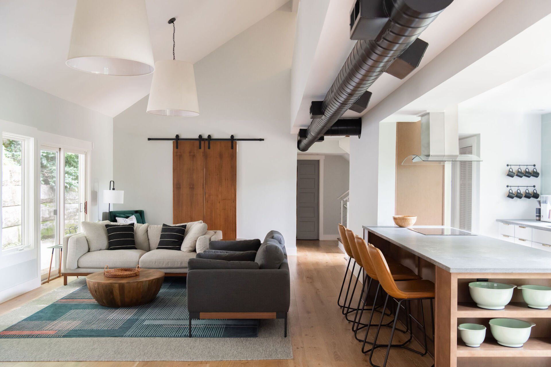 Open-plan living room and kitchen with gray sofa, wooden island, and exposed ductwork