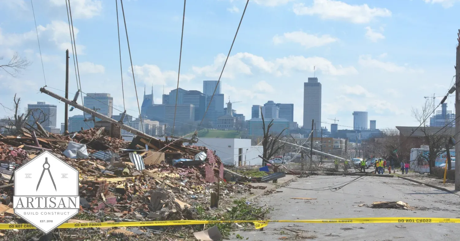 Debris-lined road with damaged buildings and a city skyline in the distance under a blue sky
