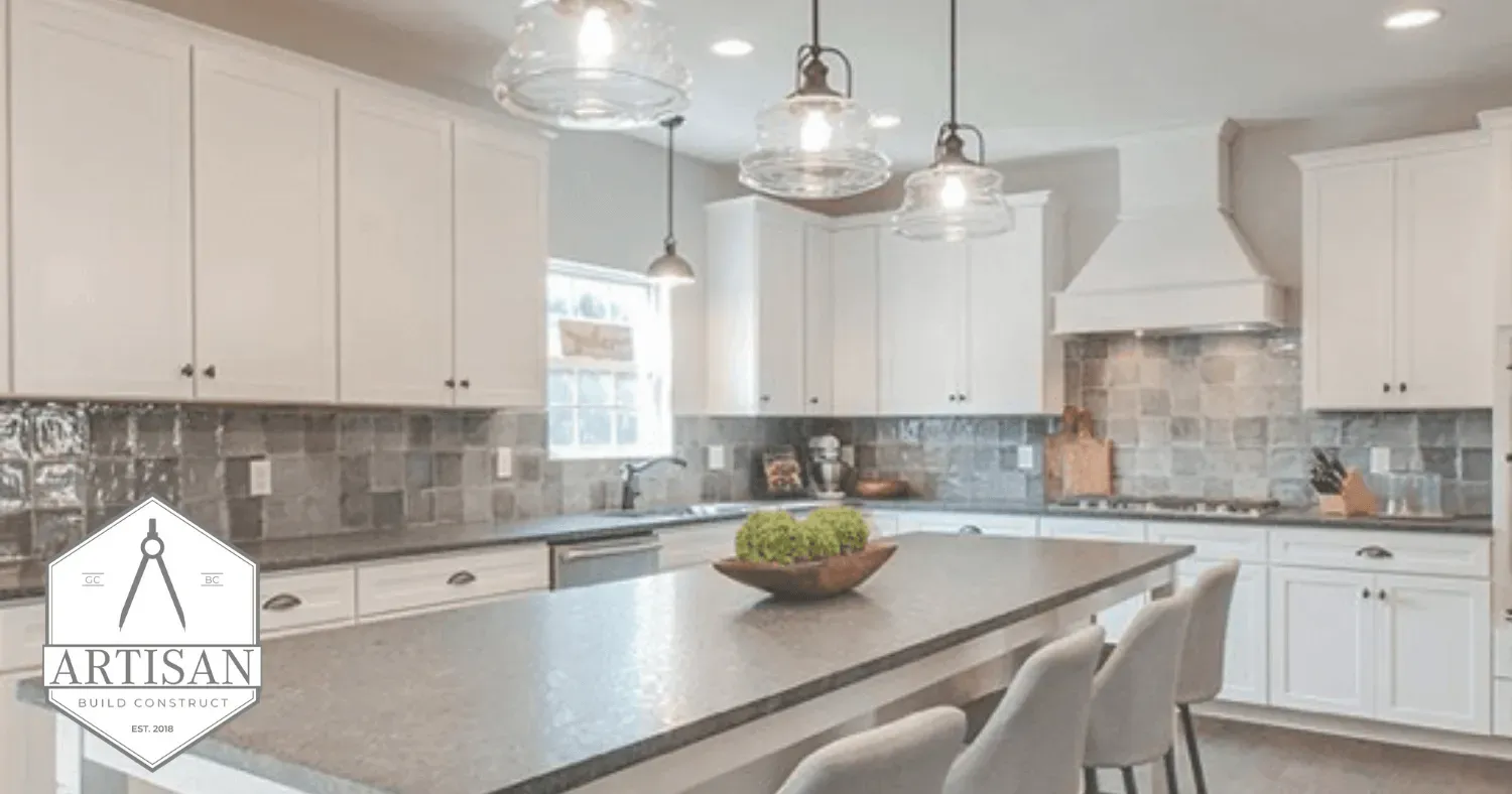 Bright modern kitchen with white cabinets, gray island, pendant lights, and tiled backsplash