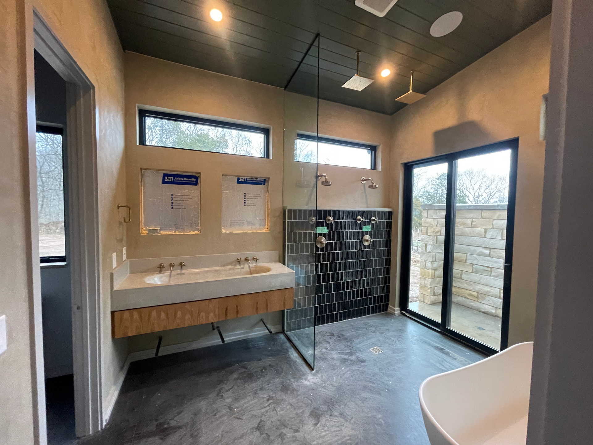Modern bathroom with double sink vanity, glass shower, and large windows in gray and wood tones