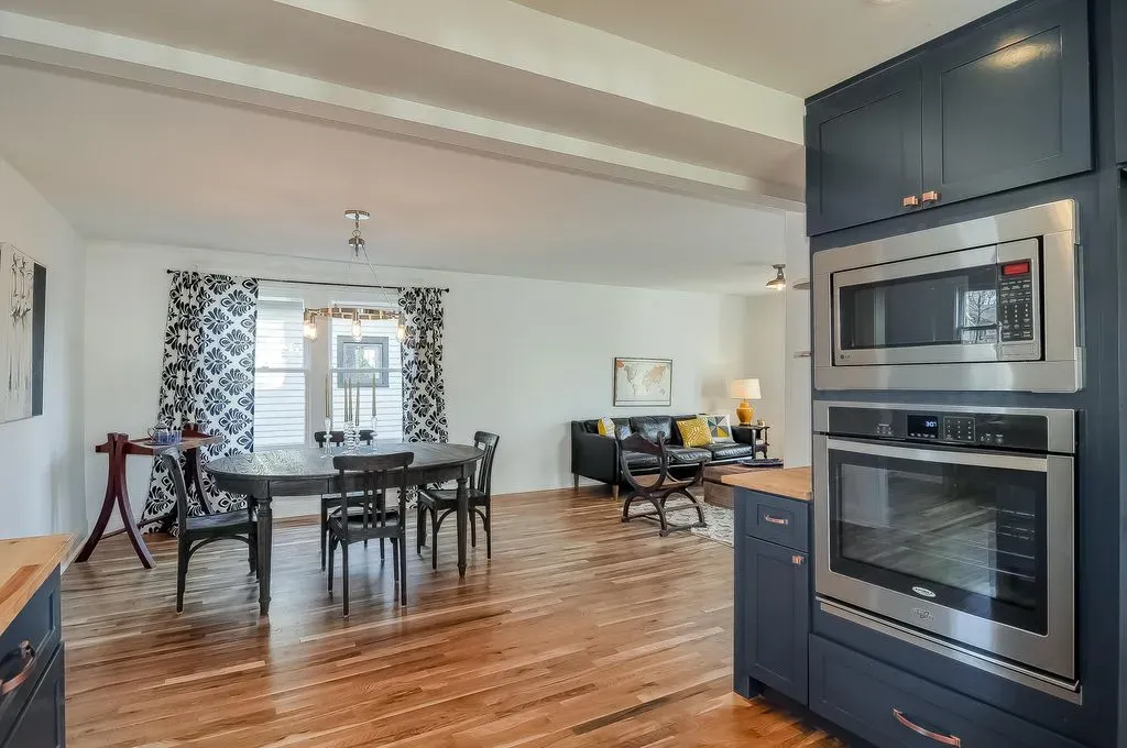 Modern kitchen and dining area with hardwood floors, dark cabinetry, and a windowed dining nook