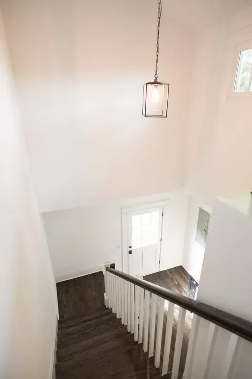 Staircase with dark wood steps, white railings, and a hanging lantern above a white entry hall.