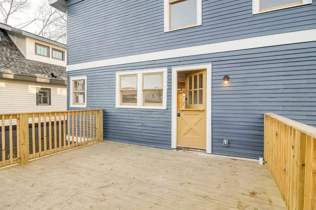 Blue house exterior with a fenced sandy patio and a back door with windows