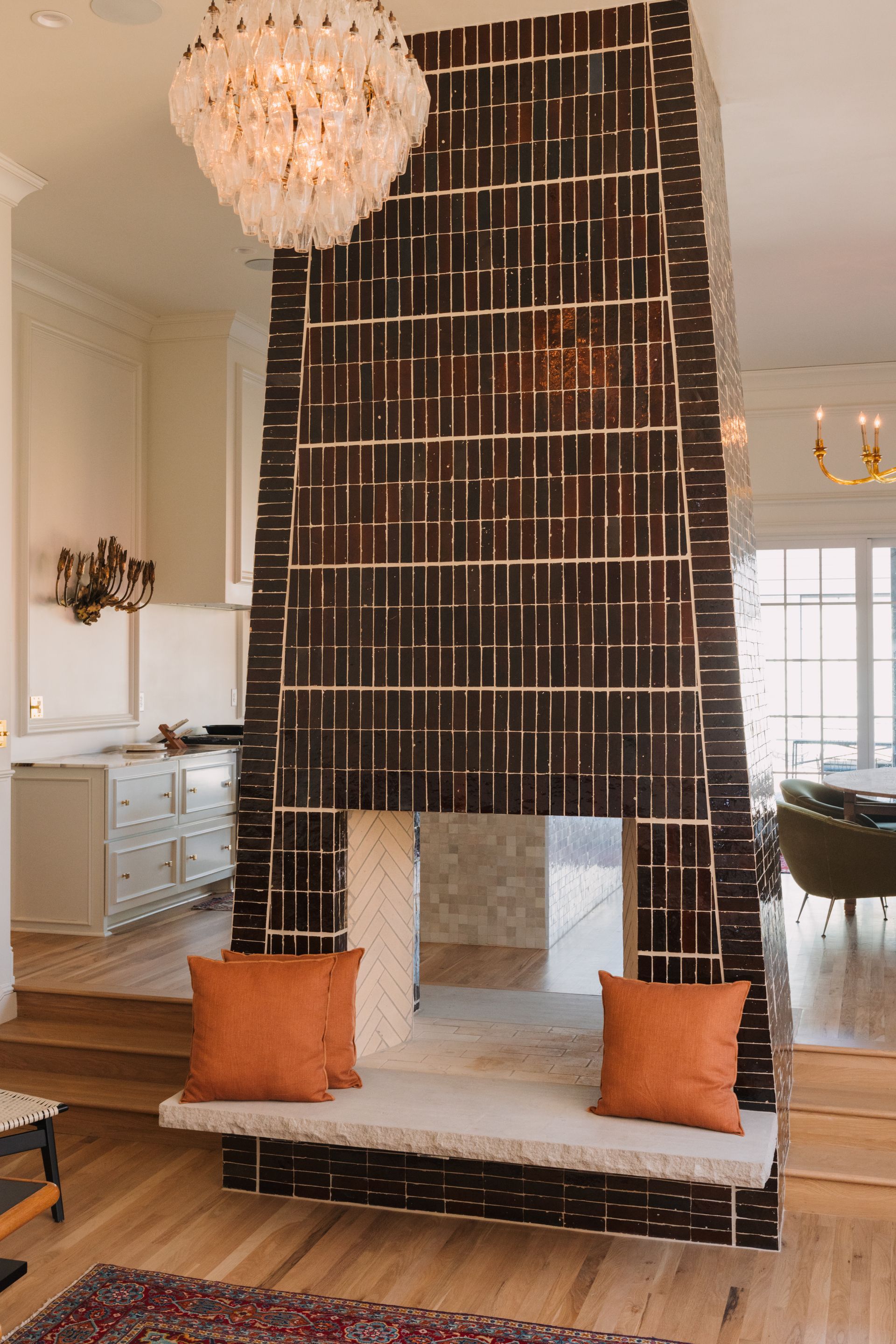 Living room with a tall black beaded room divider, orange pillows, and a chandelier overhead