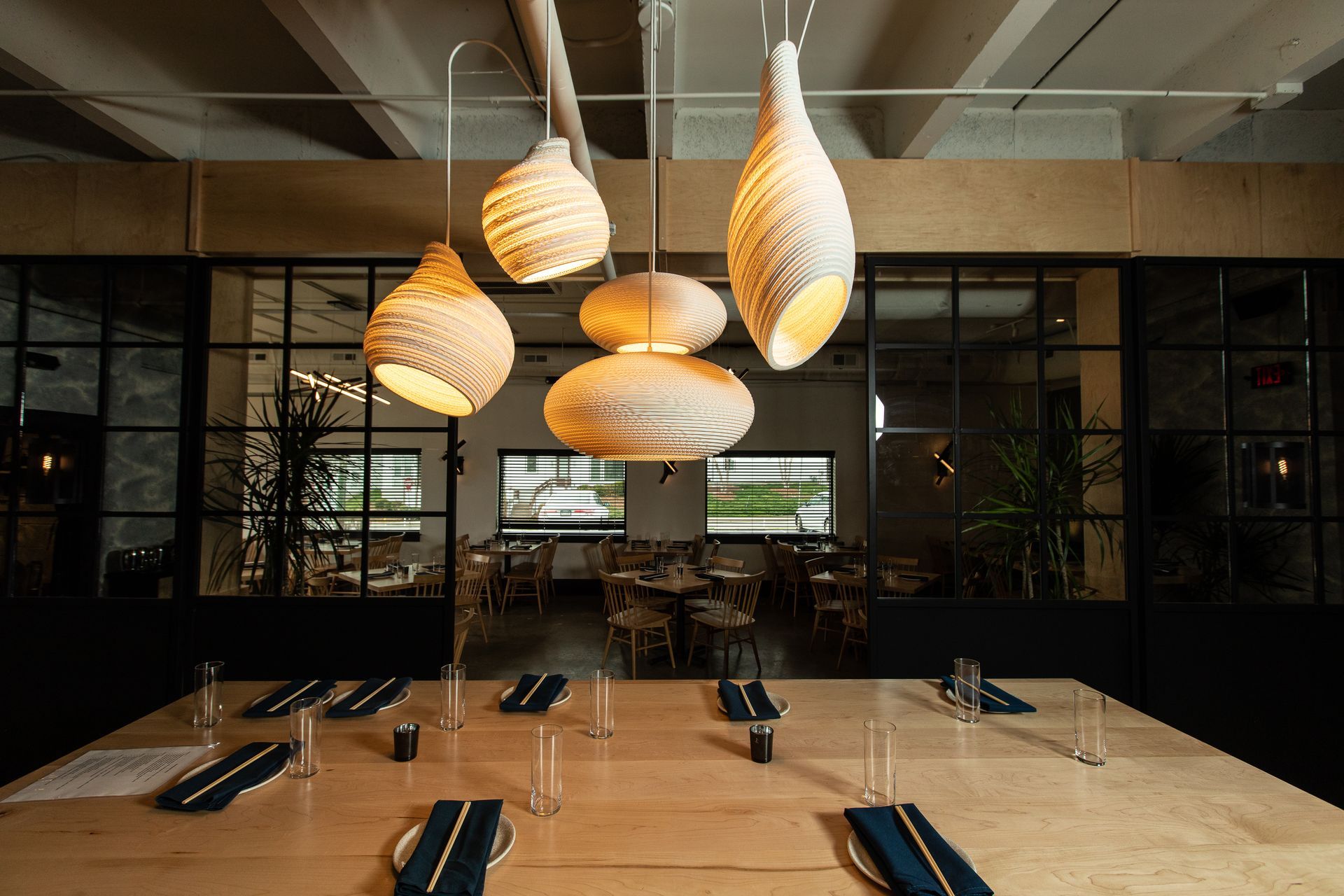 Modern restaurant interior with woven pendant lights over neatly set dining tables