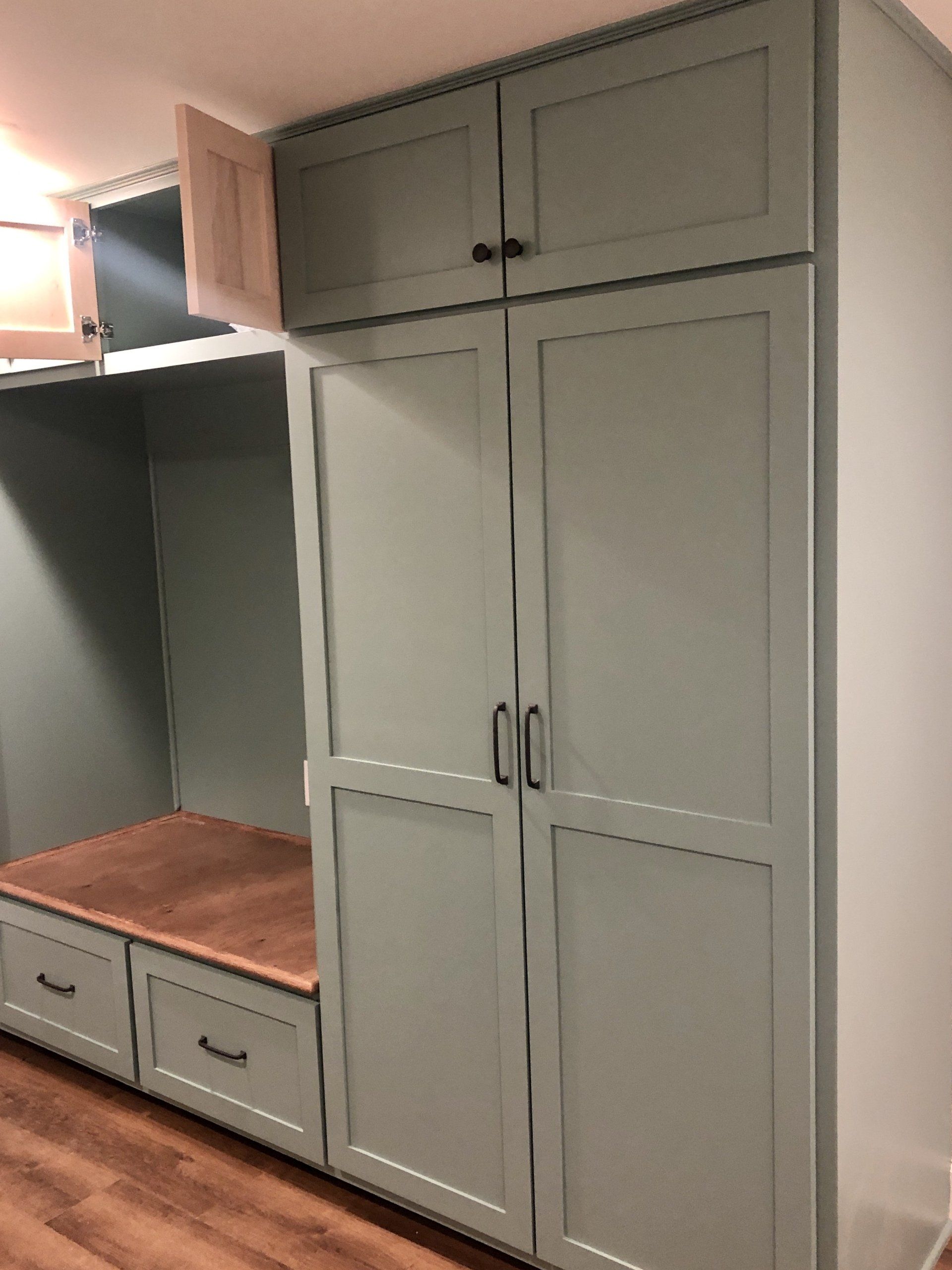 Built-in gray cabinet wall with TV nook, wood countertop, and lower drawers in a room