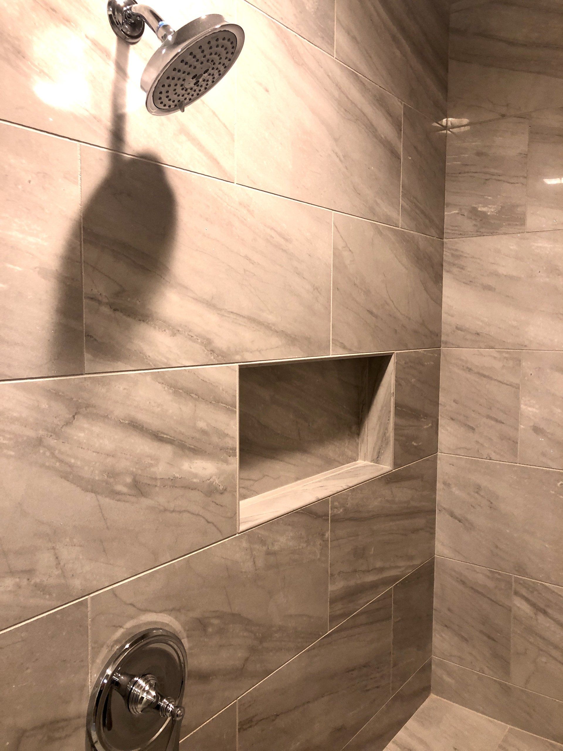 Modern shower with tiled walls, built-in niche, and two chrome shower fixtures.