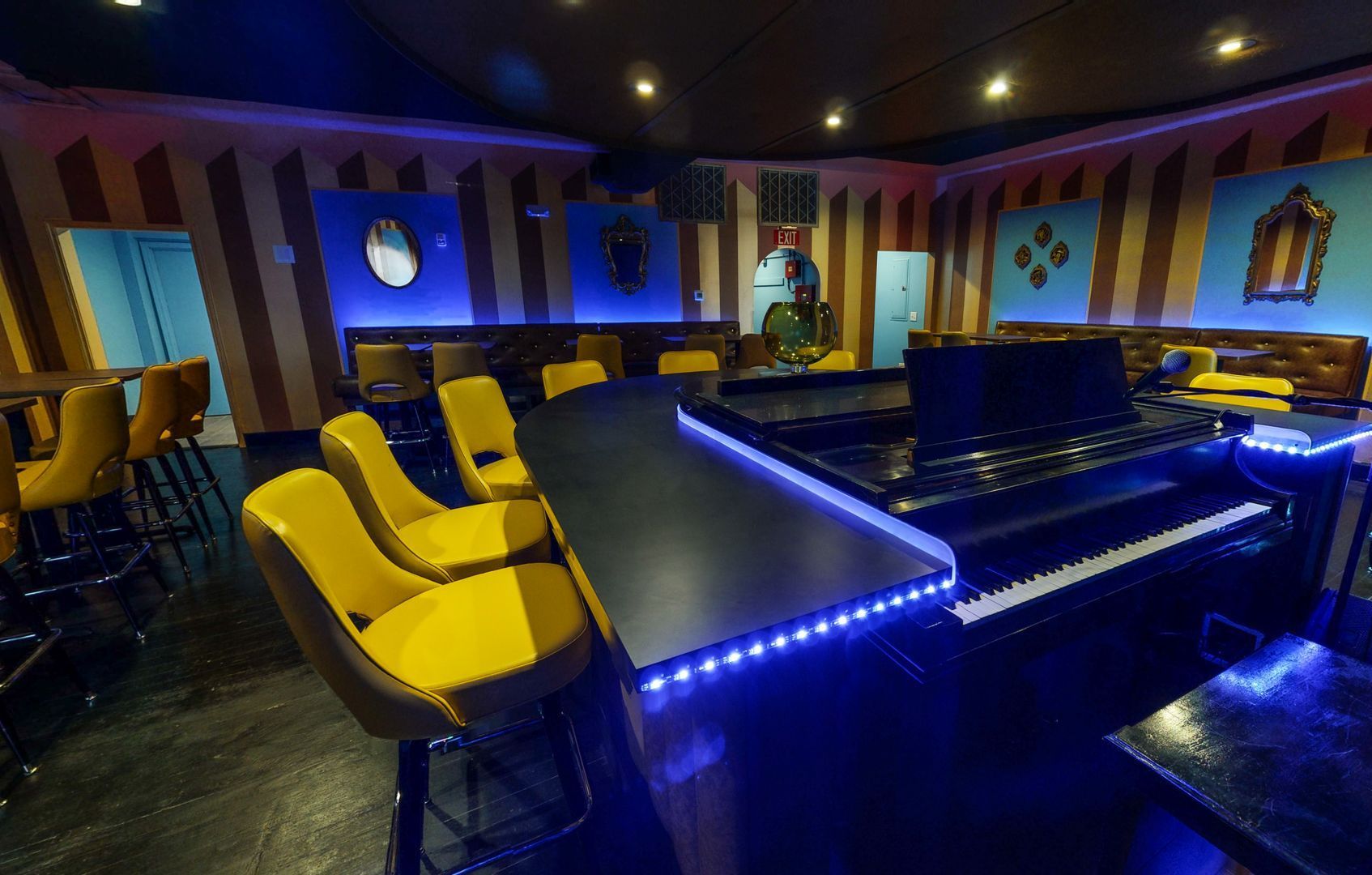 Modern lounge with yellow chairs, blue LED-lit bar, and colorful wall panels