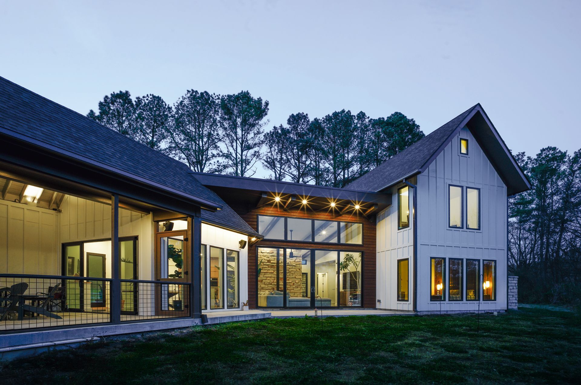 Modern house exterior at dusk with large windows and warm interior lights