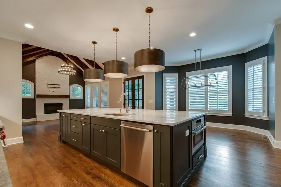 Modern kitchen with large island, dark cabinets, pendant lights, and hardwood floors