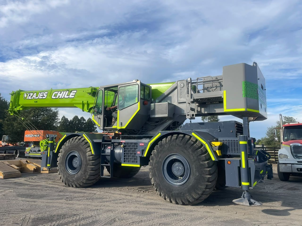 Gran máquina de construcción verde y gris en un terreno de tierra bajo un cielo nublado
