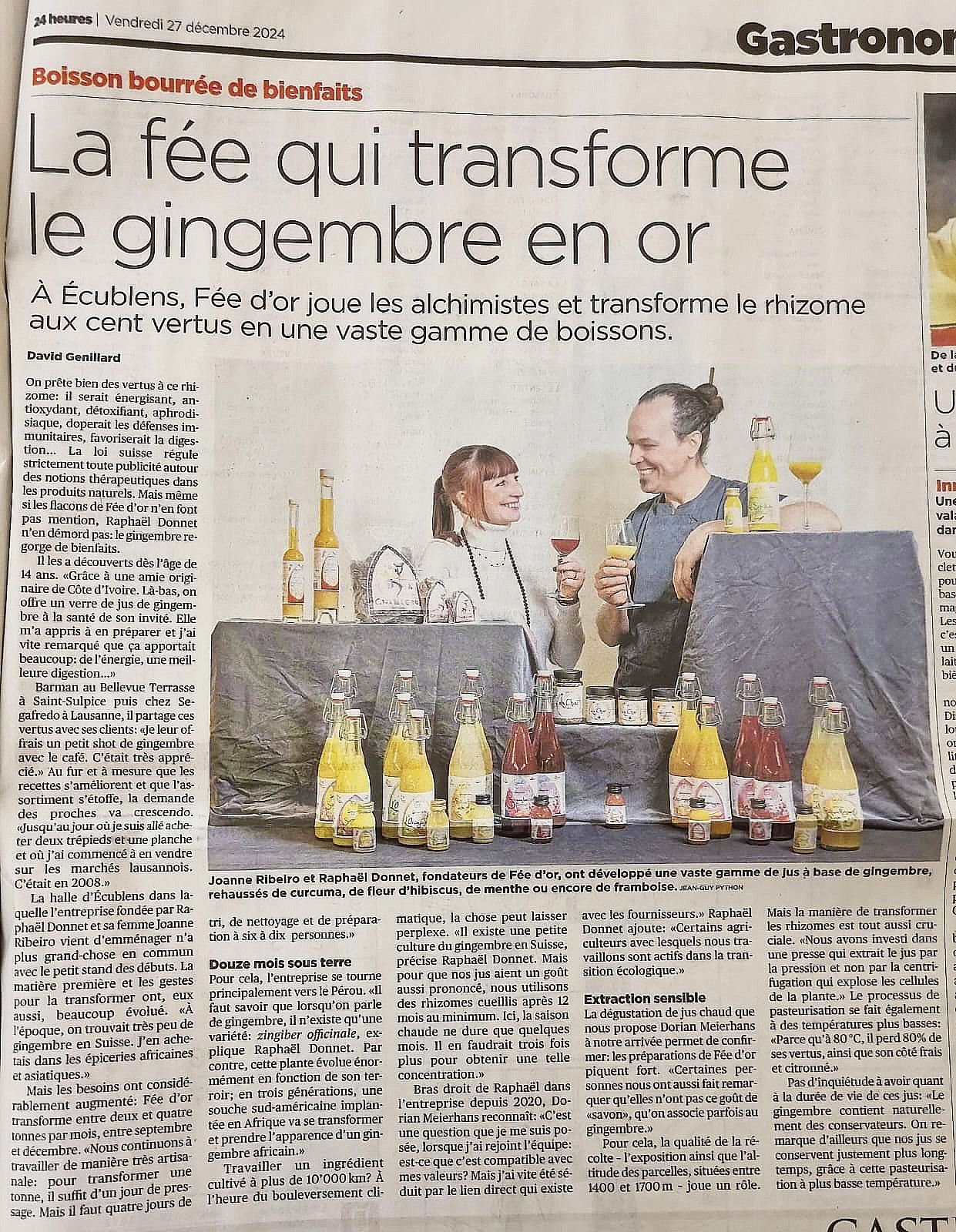 Article de journal avec photo : Deux personnes se tiennent derrière une table de boissons colorées au gingembre.