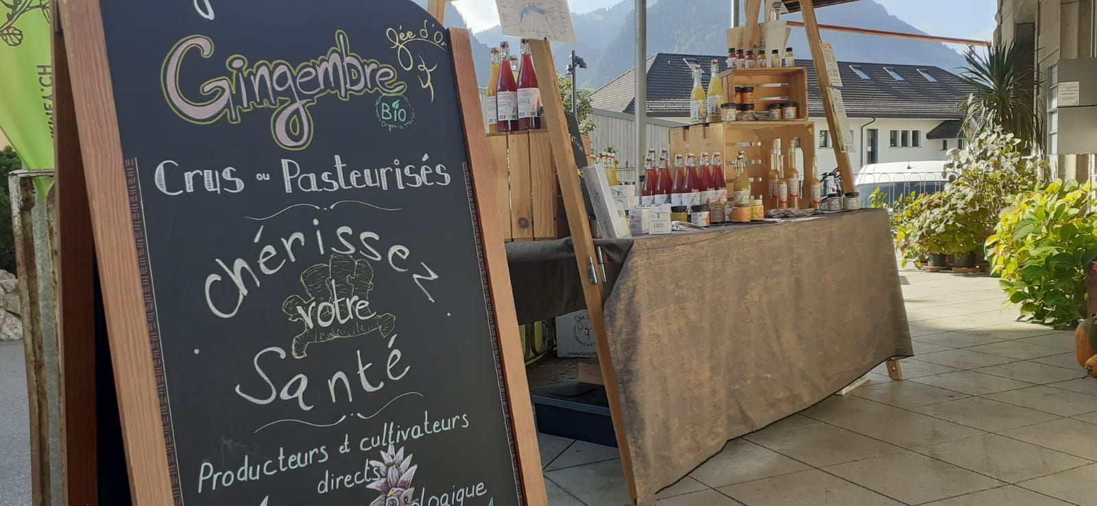 Une ardoise devant un étal de marché vendant des produits à base de gingembre.