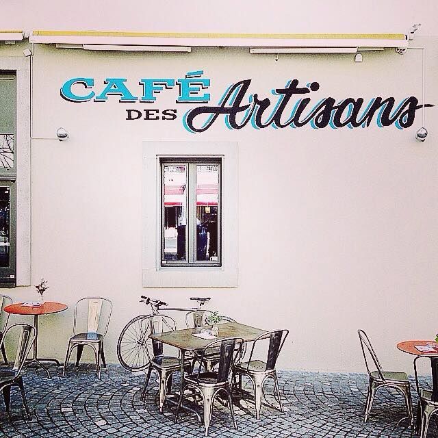 Extérieur du café « Des Artisans » avec terrasse, vélo et patio pavé.