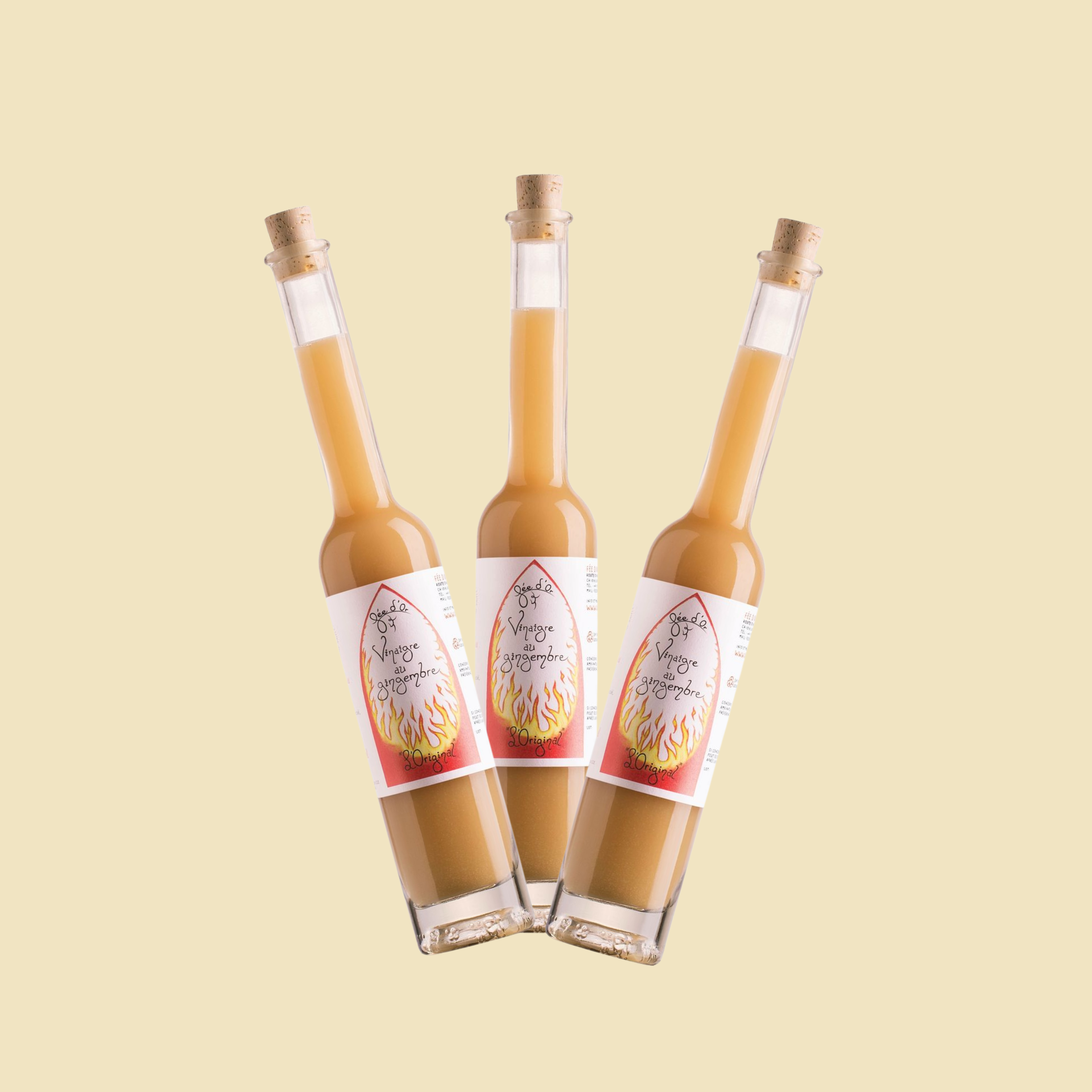 Trois bouteilles inclinées contenant un liquide orange clair, chacune portant une étiquette représentant une moitié de fruit du dragon sur fond crème.
