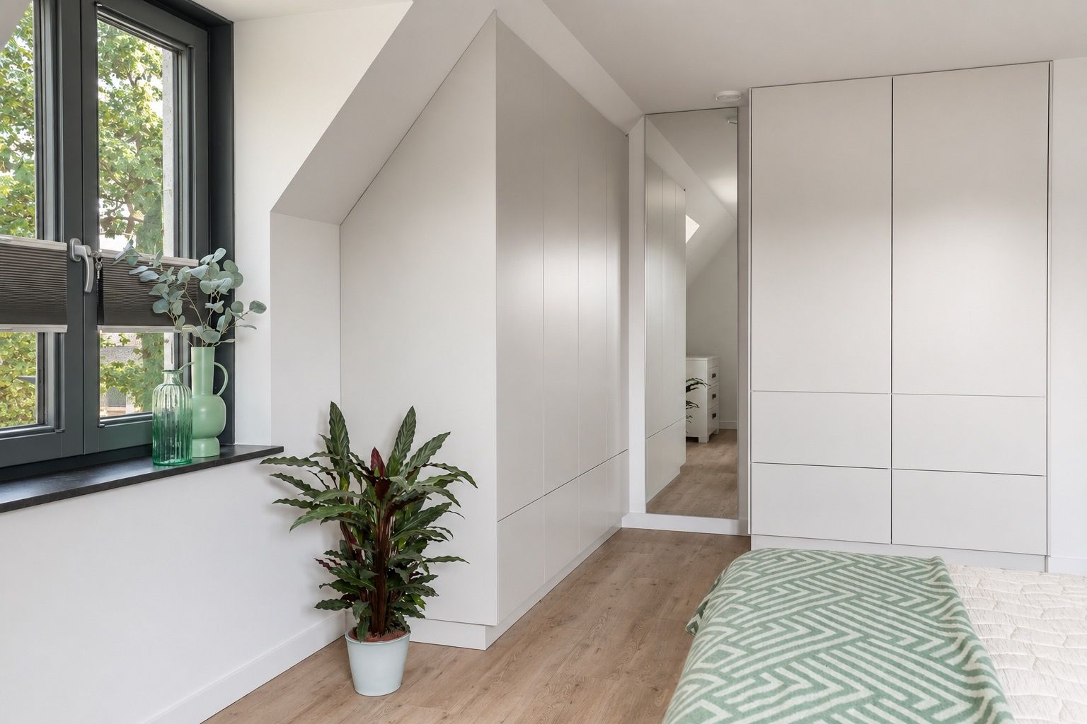 Ruime kamer met een lange houten eettafel, zwarte stoelen, een grote kast en prachtige kamerplanten in een modern penthouse.