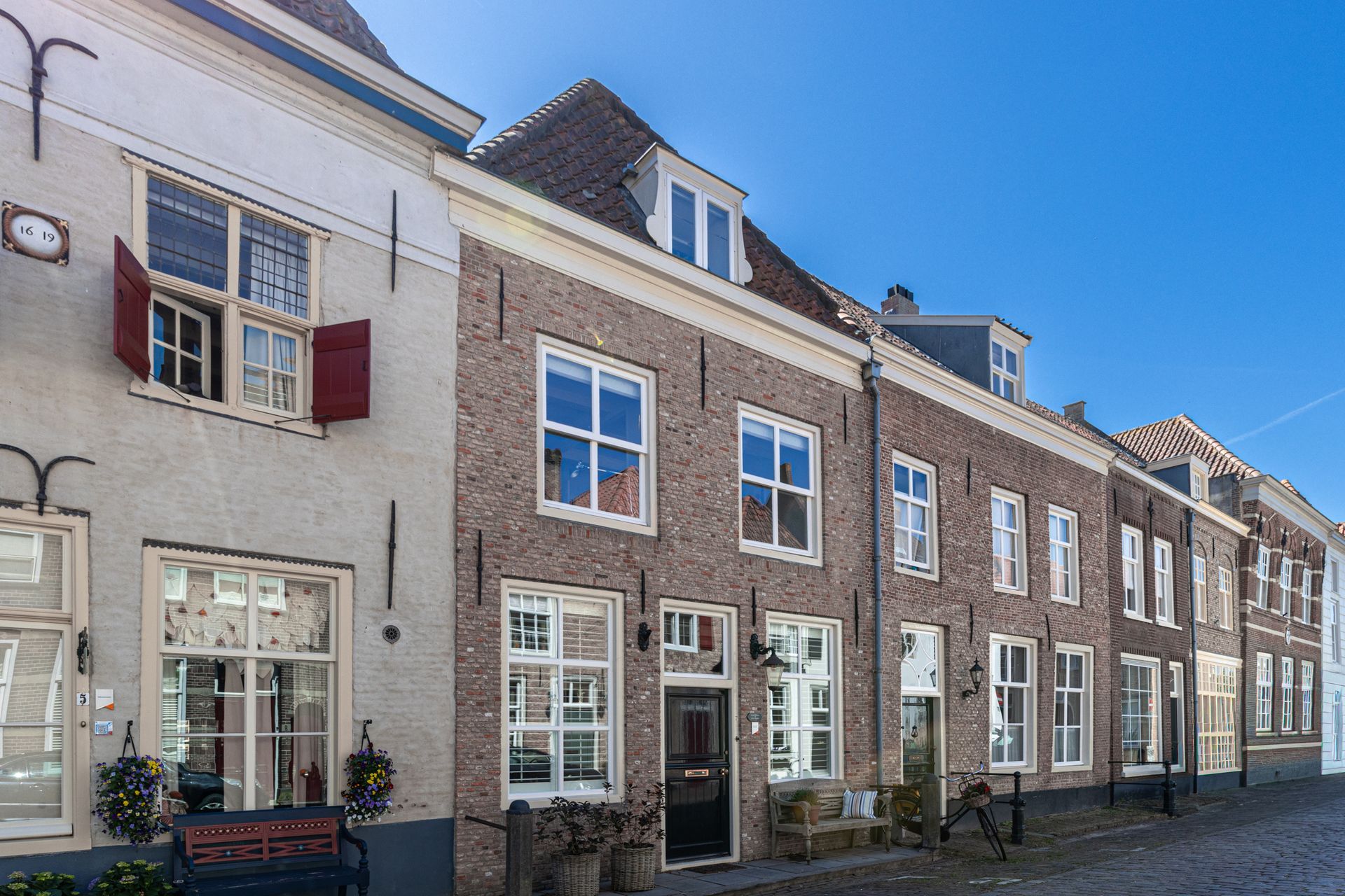 Ruime kamer met een lange houten eettafel, zwarte stoelen, een grote kast en prachtige kamerplanten in een modern penthouse.