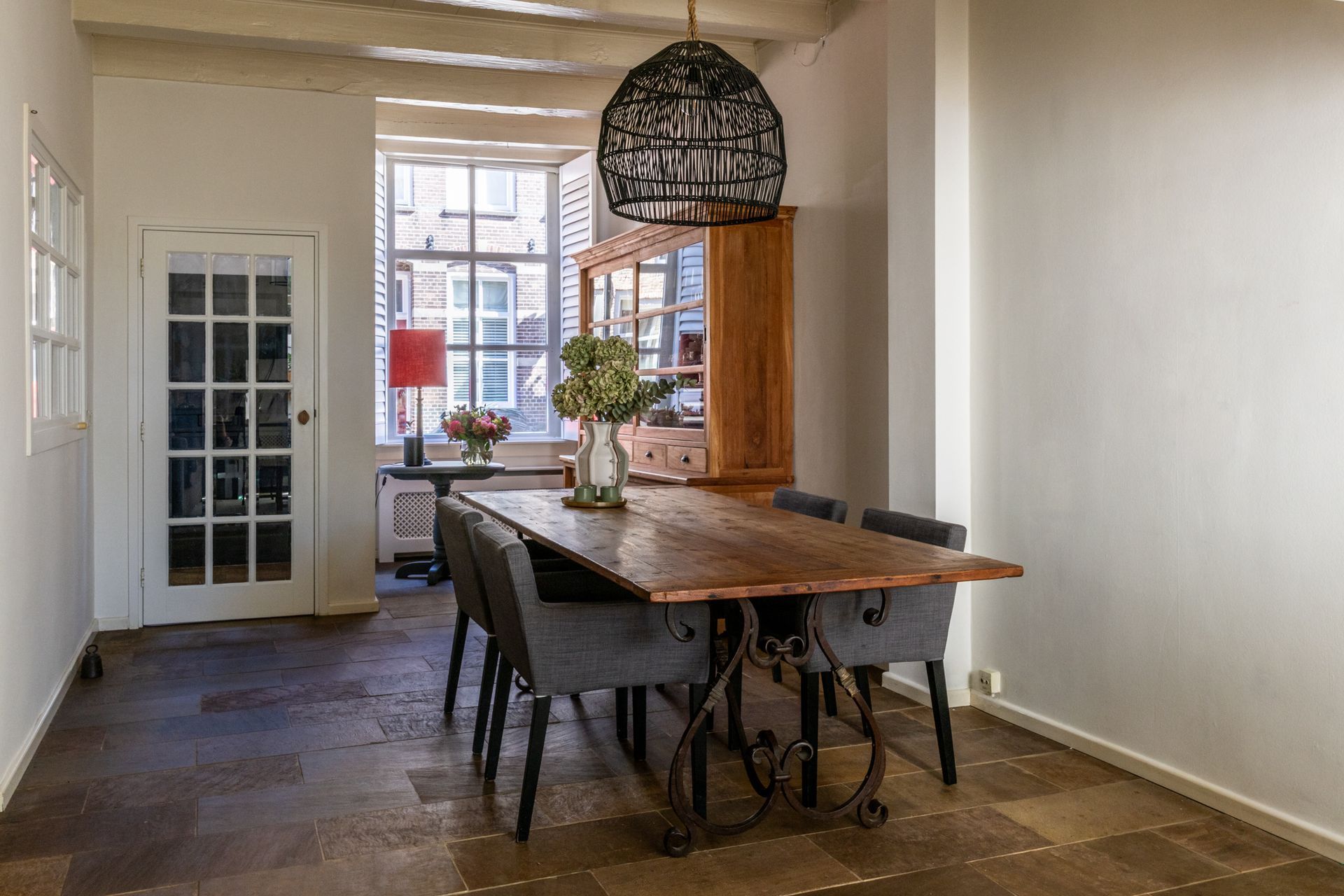 Een moderne woonkamer met maar liefst ruimte voor 3 royale banken. In beige en zwart, en een zwarte sofa, een houten salontafel, een hoogpolig vloerkleed en grote ramen van vloer tot plafond, die toegang geven tot het zeer grote balkon.