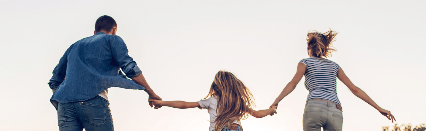 a family is holding hands and running in a field
