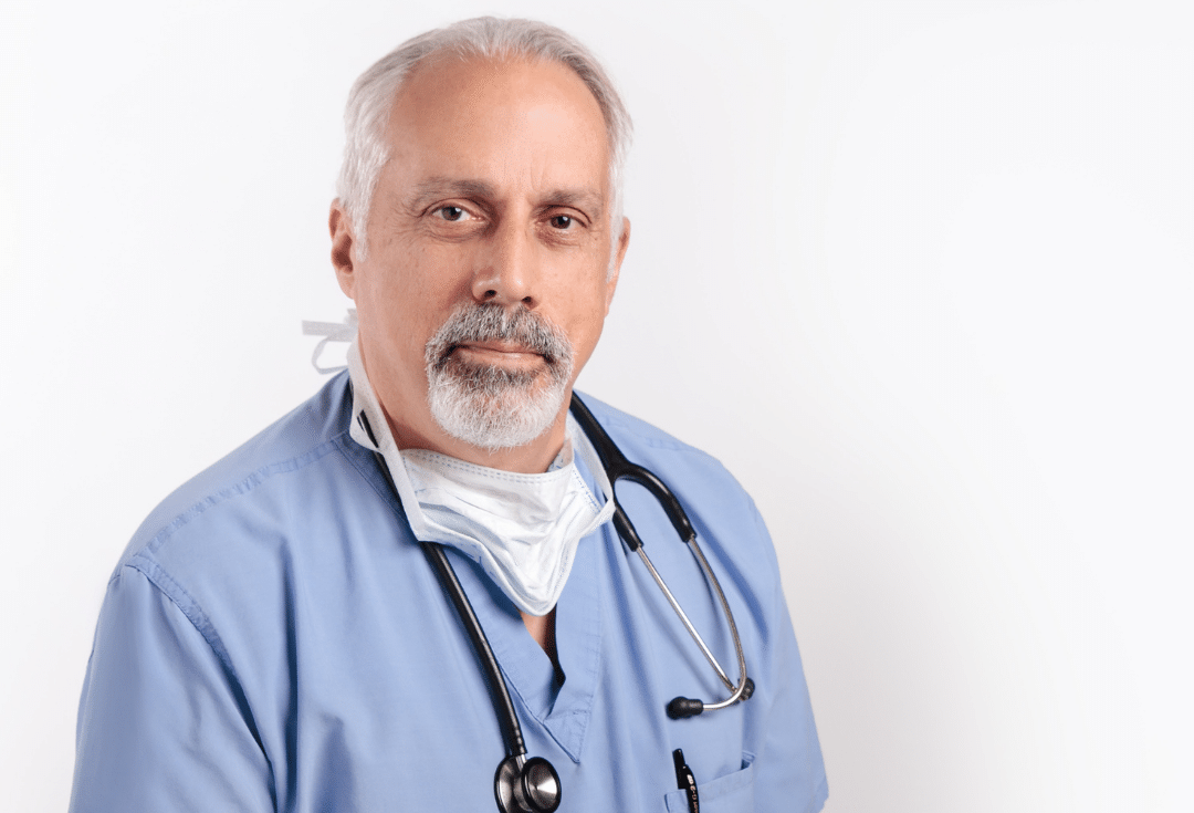 Doctor Mark Garwin of The Albany Clinic in Carbondale wearing a mask and stethoscope looks at the camera