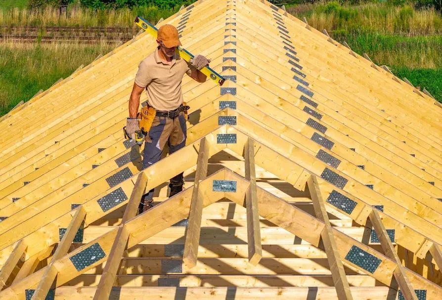 Worker wearing safety gear on a wooden roof frame under construction