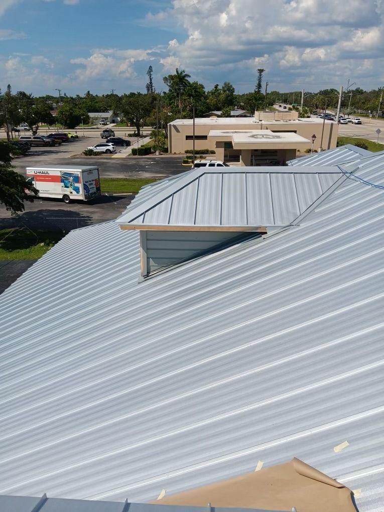 Rooftop with silver metal panels overlooking a parking lot and low commercial buildings under a clear sky