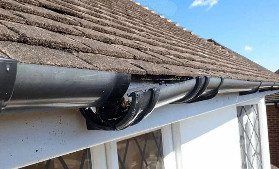 Sagging black cable under a roof gutter beside a tiled house roof