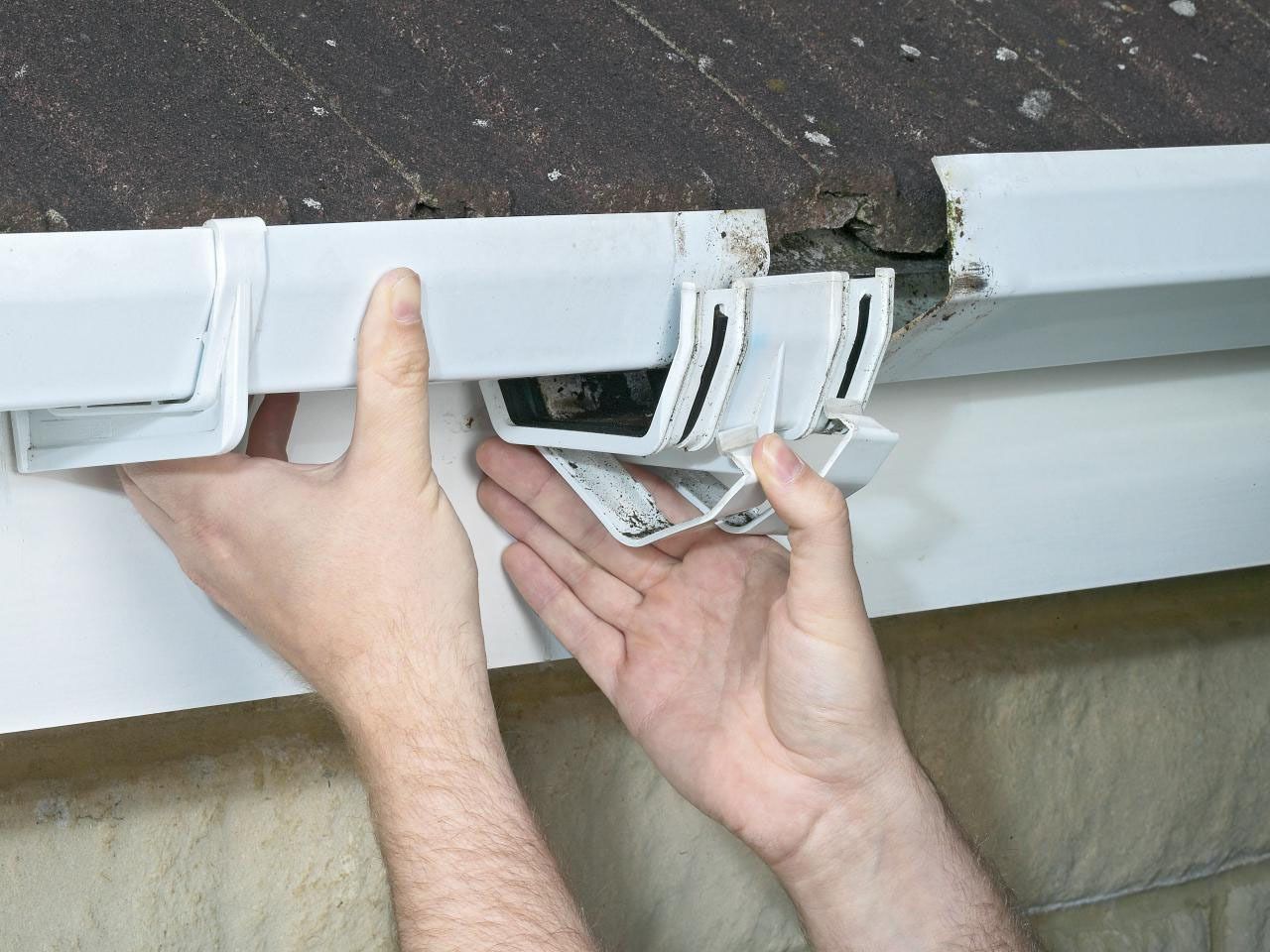 Hands adjusting white window blinds and bracket hardware on a wall-mounted track.