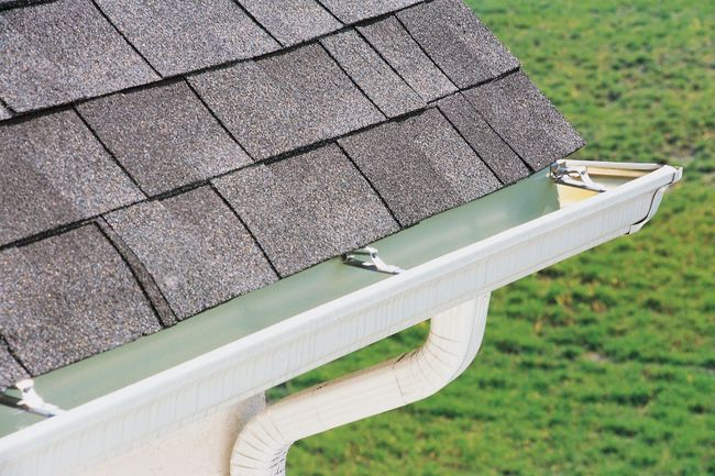 Green gutter on a dark gray shingled roof, with a close-up view of the roof edge